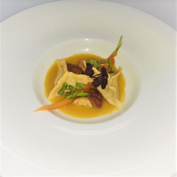 Obrázek z Ravioli plněné kuřecími játry, žampióny a jablky, podávané na šafránovo-zeleninové omáčce.